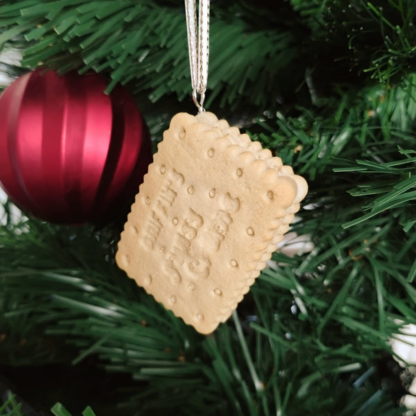 Biscuit-shaped ornament on a Christmas tree with a red ball in the background