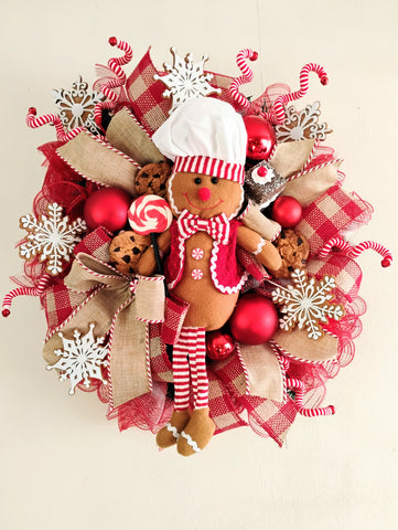 Decorative wreath with gingerbread man, candy, and festive ribbons on a beige background