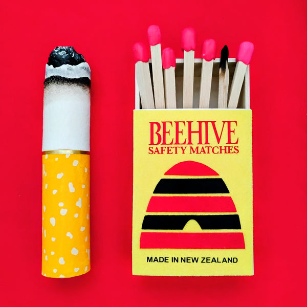 Matchstick and matchbox with 'Beehive Safety Matches' branding on a red background