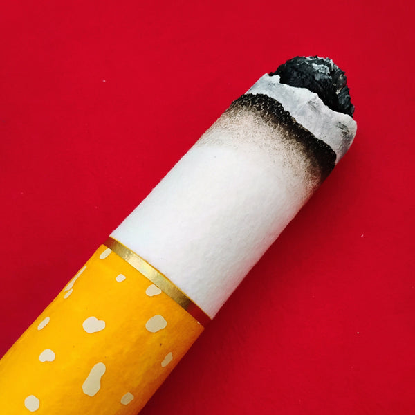 Large scale cigarette with a lit end on a red background