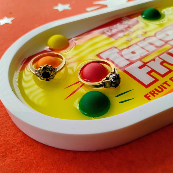 Two gold rings on a yellow tray with 'Fruity Fruits' branding on a red background