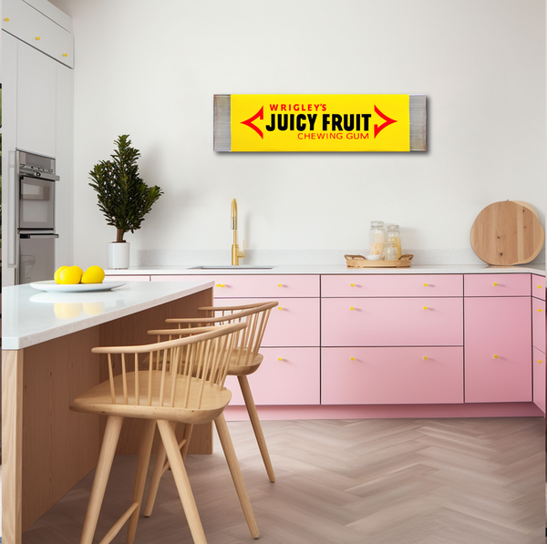 Modern kitchen with pink cabinets, wooden chairs, and a Juicy Fruit sign on the wall.