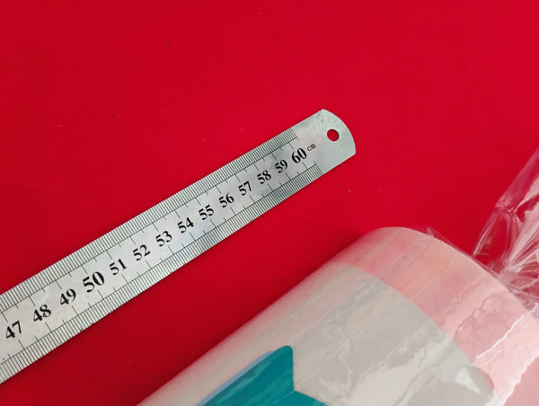 Metal ruler on a red background with a partially visible product underneath, showing length of item
