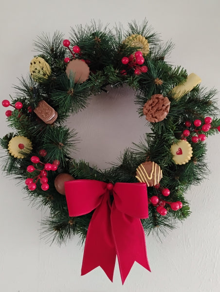 Christmas wreath with red bow, NZ biscuits and berries on a plain background