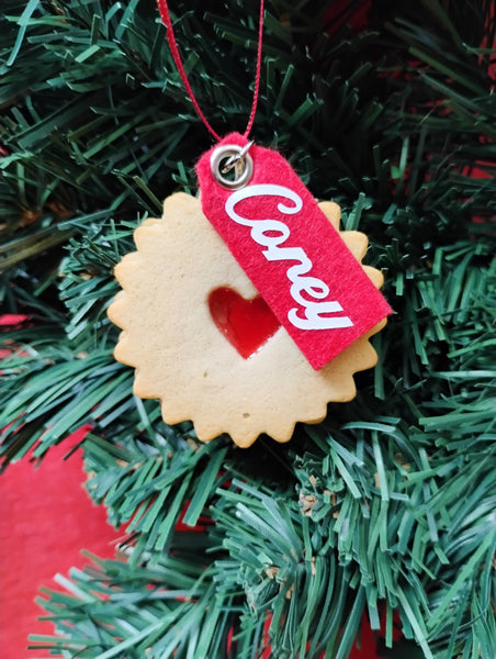 Decorative cookie ornament with a red tag labeled 'Corey' on a Christmas tree.