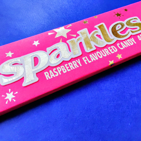 Pink packaging of Sparkles raspberry flavoured candy on a blue background