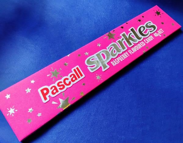 Pink packaging of Pascall Sparkles raspberry-flavoured candy on a blue background