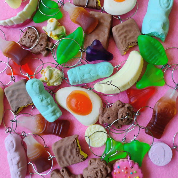Collection of colorful miniature food wine charms on a pink background