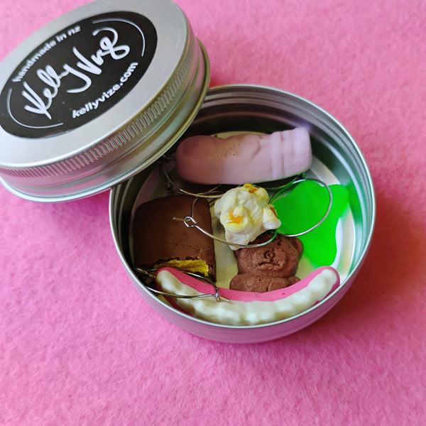 Small tin with a set of wine charms on a pink background