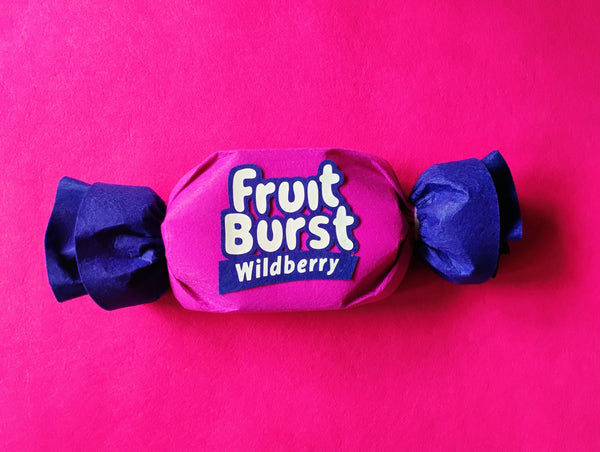 Fruit Burst Wildberry candy in pink and blue wrapper on a pink background